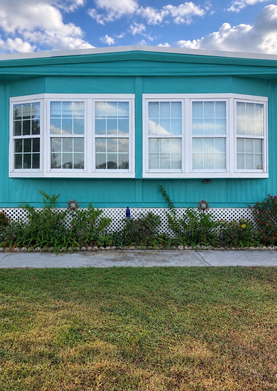 Same home after Hue Painting repainted the siding and trim in bright teal with crisp white window frames, Polk County FL