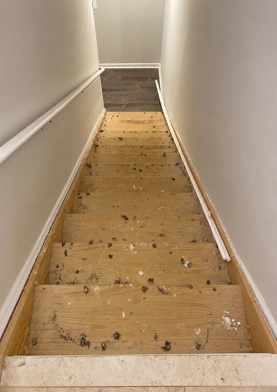 Staircase before refinishing, bare treads covered in old carpet staples and paint spots, Lakeland FL